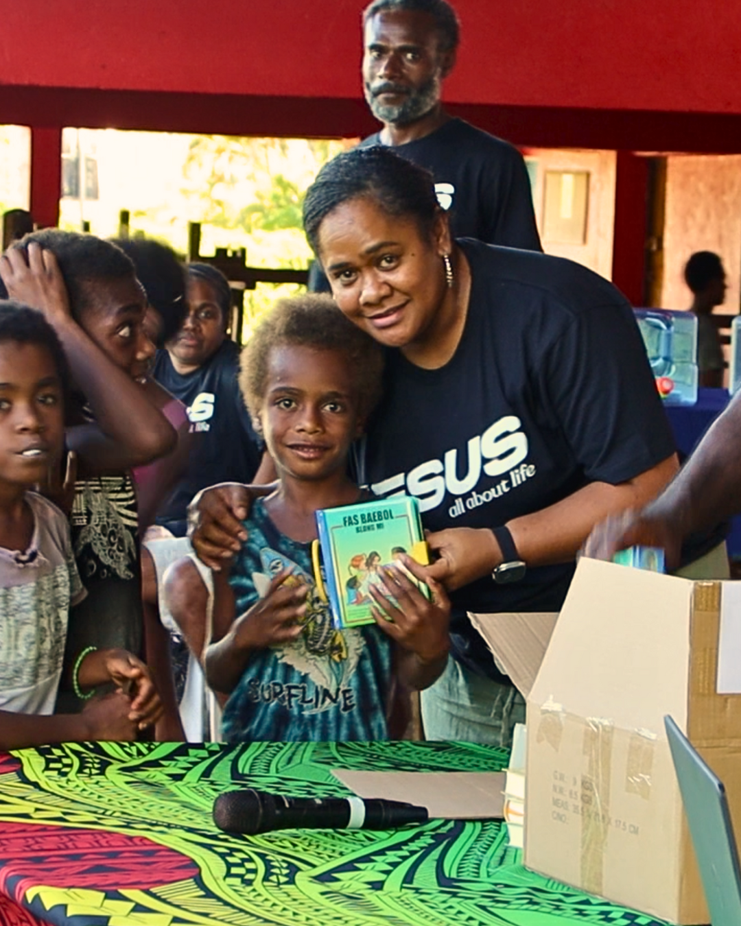 Medewerker Pacific Bijbelgenootschap deelt Bijbel uit aan kind